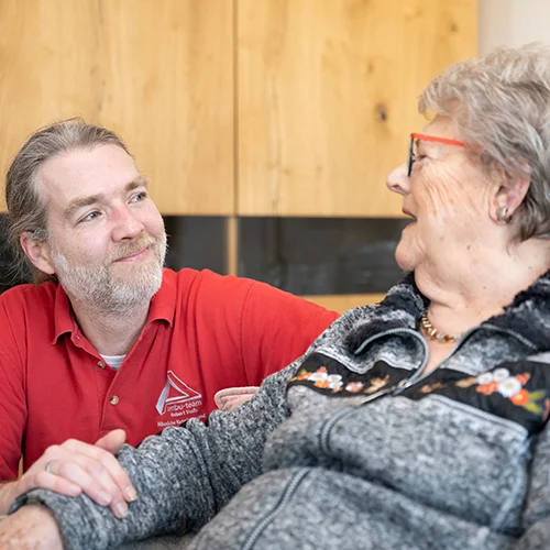 Mitarbeiter des Ambu-Teams aus dem Kreis Düren behandelt eine lächelnde Patientin fürsorglich und herzlich.